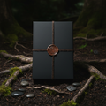 Dark brown crescent moon wax sealed box on dark soil surrounded by roots moss and river stones